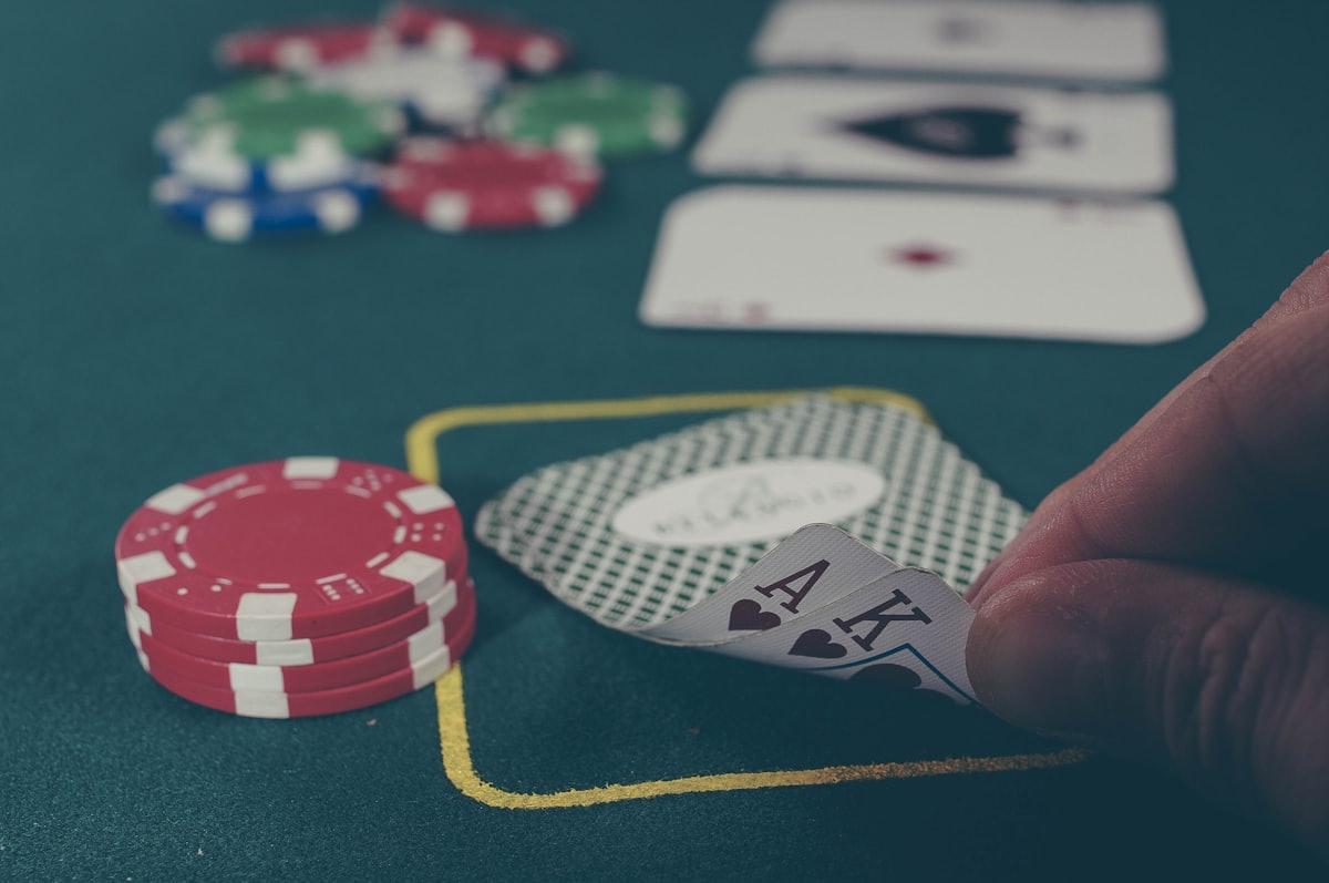Keping poker dan kartu remi tersebar di atas meja felt hijau