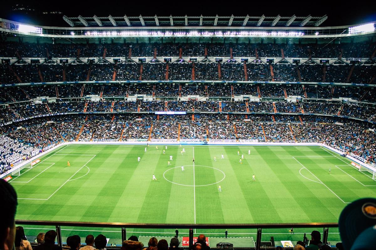 Stadion sepak bola penuh penonton dengan lapangan hijau terang