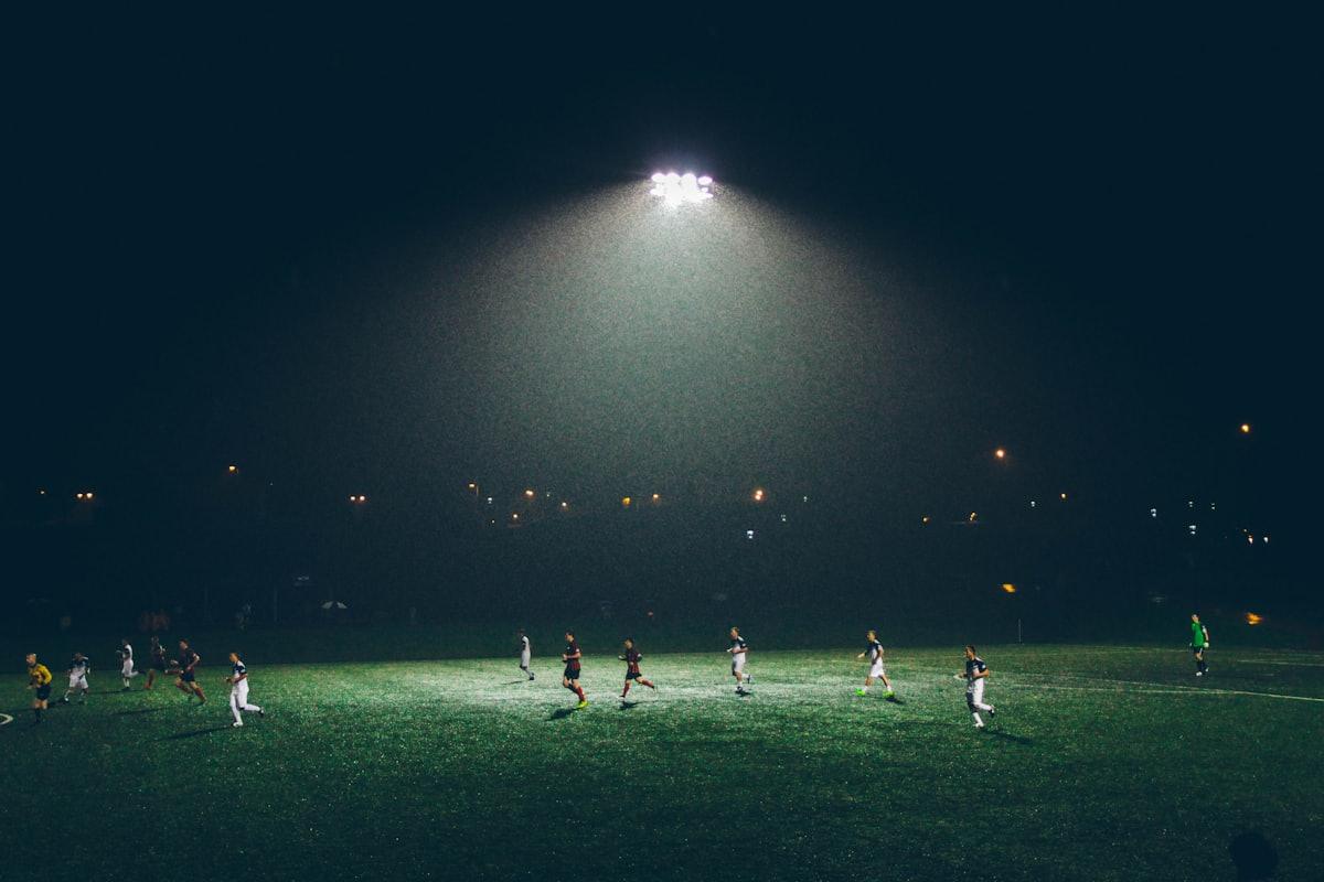Lapangan sepak bola di malam hari dengan lampu sorot stadion menyala